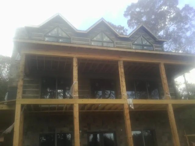 Dormers and porch framing on a large log home under construction — Roof Coating work by our crew in Thief River Falls