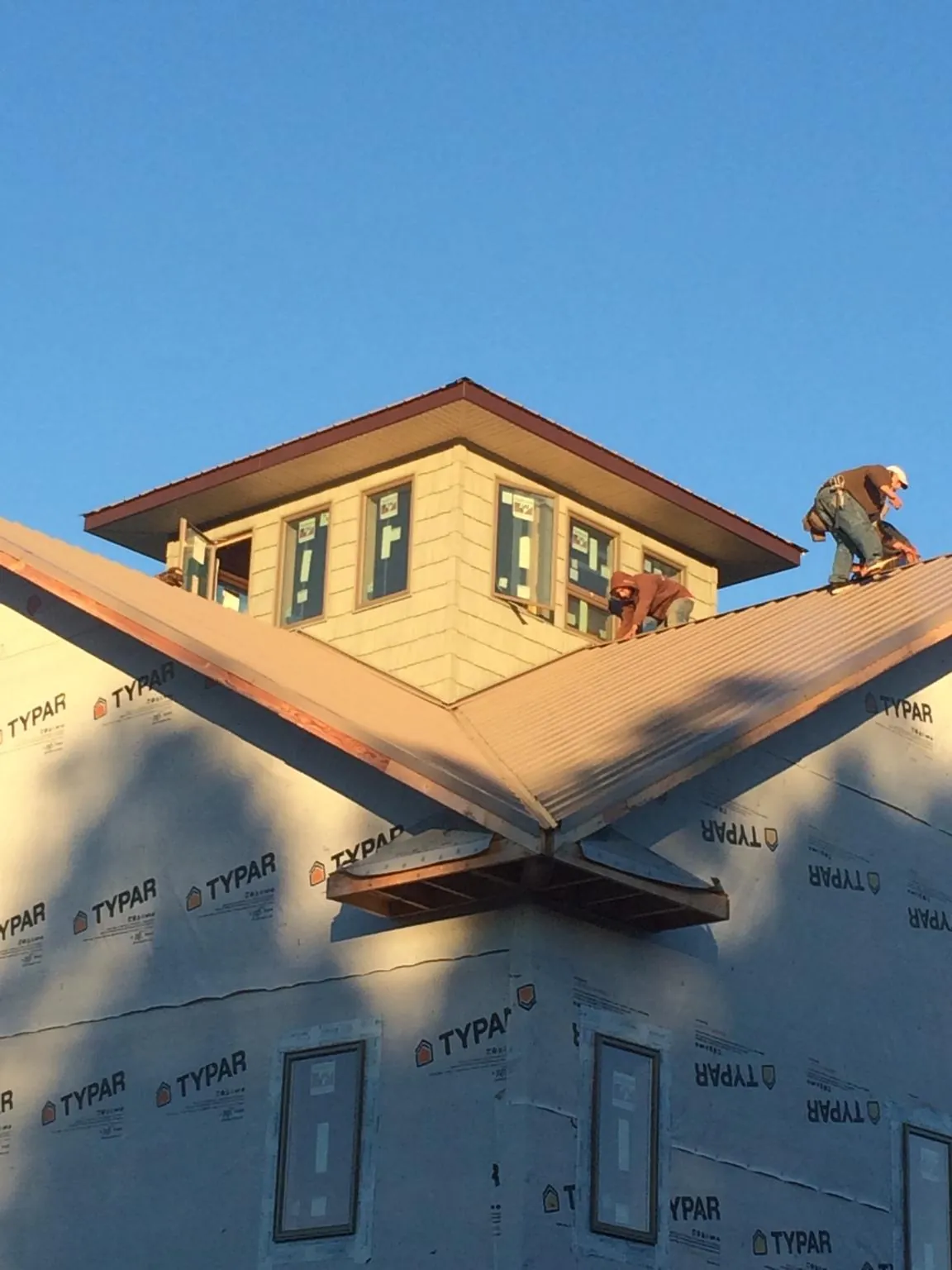 Roofers working around a rooftop cupola on a new metal roof at sunset — Roof Waterproofing in Thief River Falls by Roofing Brothers